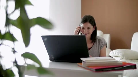 Slow motion of a nice girl browsing laptop and talking over phone at home 스톡 동영상 49829119