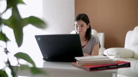 Slow motion of a nice girl browsing laptop and answering phone at home Stock Footage 49832812