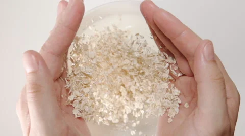 SLOW MOTION: Oat flakes falls from a human hands to the milk in a dish Stock Footage 65172826