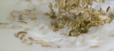 Slow motion oatmeal flakes falling into milk Stock Footage 323438796