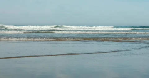 Slow-motion ocean surf lines rolling over wet sand, wide Stock Footage 318594288