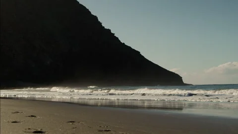 Slow Motion Ocean Wave, sandy coastline with mountains Stock Footage 247074623