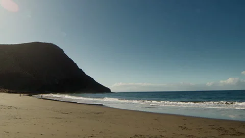 Slow Motion Ocean Wave, sandy coastline with mountains Stock Footage 247075771