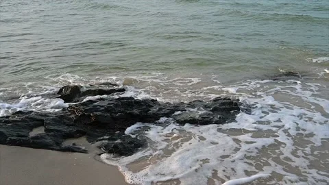 Slow motion ocean wave splashes across a big rock in the middle of the rough exo Stock Footage 194997675