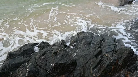 Slow motion ocean wave splashes across a big rock in the middle of the rough exo Stock Footage 219721481