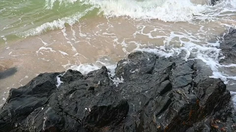 Slow motion ocean wave splashes across a big rock in the middle of the rough exo Stock Footage 219721485