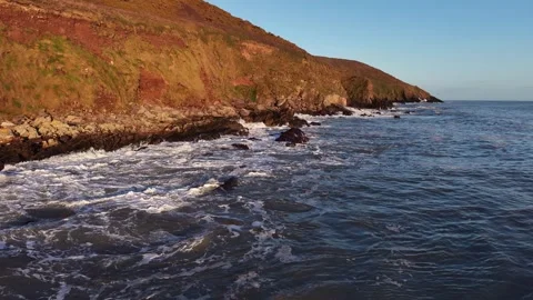 Slow Motion Ocean Waves Along Sunlit Coastal Hillside in 4K 库存影片 332944427