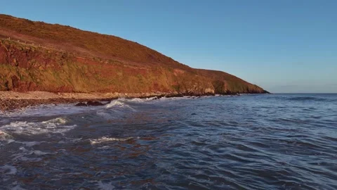 Slow Motion Ocean Waves Along Sunlit Coastal Hillside in 4K Stock-Footage 332944450