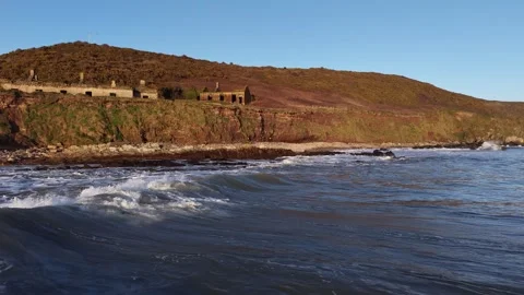 Slow Motion Ocean Waves Along Sunlit Coastal Hillside in 4K Stock-Footage 332944451