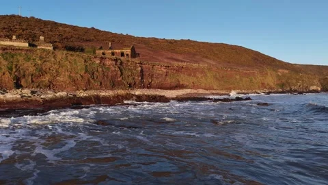 Slow Motion Ocean Waves Along Sunlit Coastal Hillside in 4K 库存影片 332944465