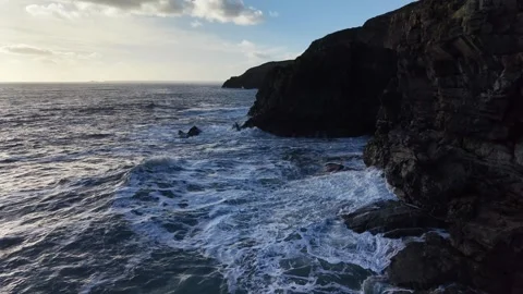 Slow Motion Ocean Waves Along Dark Rocky Coastline in 4K Stock Footage 332944696