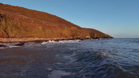 Slow Motion Ocean Waves Along Sunlit Coastal Hillside in 4K Stock-Footage 332944816