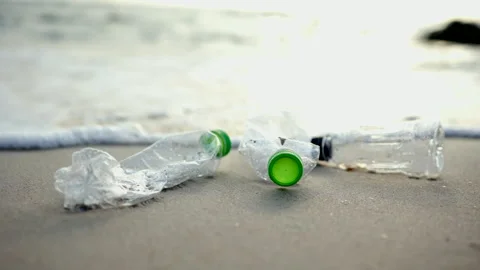 Slow motion Ocean waves are washing plastic bottles from the beach into the sea. Stock Footage 172182567