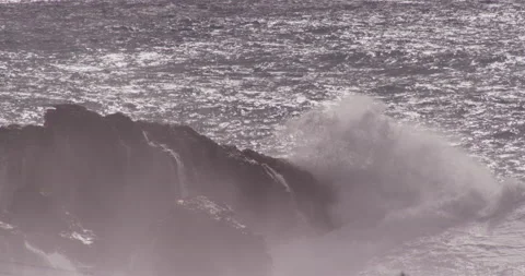 Slow motion of ocean waves coming up to big boulders and splashing against it Stock Footage 156141652