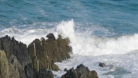 Slow motion ocean waves crash onto rocks and spray Stock Footage 271115894