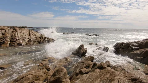 Slow motion ocean waves splash against rocks on the beach in summer 動画素材 132936679