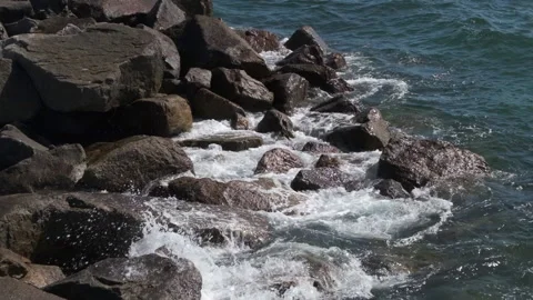 Slow motion ocean waves splashing over rocks on shore, close up. Video stock 132210029