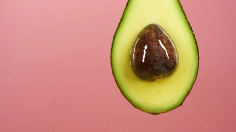 Slow motion of oil drop dripping from fresh avocado fruit over pink background Vídeo Stock 151129599