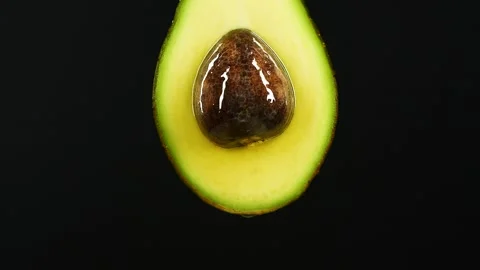 Slow motion of oil drop dripping from fresh avocado fruit over black background Vídeo Stock 151239037