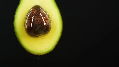 Slow motion of oil drop dripping from fresh avocado fruit over black background Stock Footage 151663014