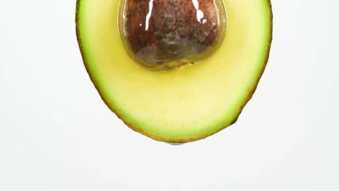 Slow motion of oil drop dripping from fresh avocado fruit over white background Stock Footage 152276544