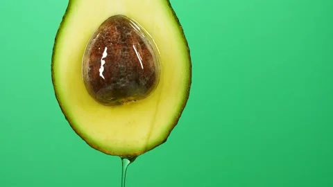 Slow motion of oil liquid splasing from fresh avocado fruit on green background Stock Footage 156725993