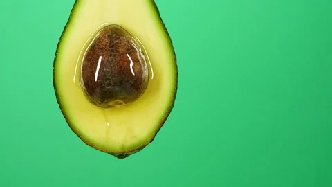 Slow motion of oil liquid splasing from fresh avocado fruit on green background Stock Footage 158073215