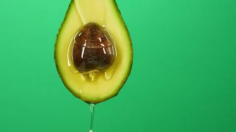 Slow motion of oil liquid splasing from fresh avocado fruit on green background Stock Footage 159395406