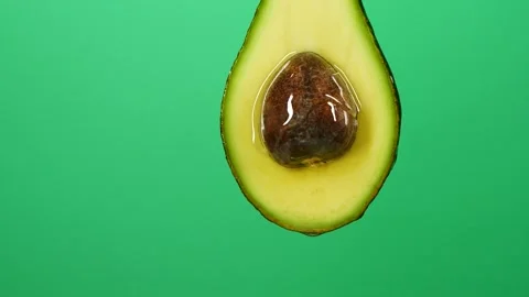 Slow motion of oil liquid splasing from fresh avocado fruit on green background Stock Footage 160241985