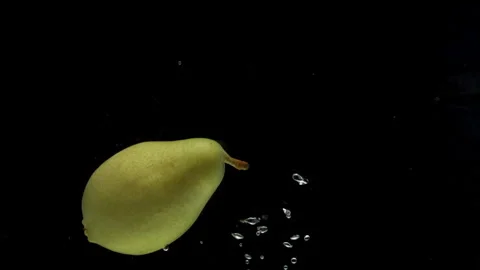 Slow motion one pear falling into transparent water on black background Video stock 258570122