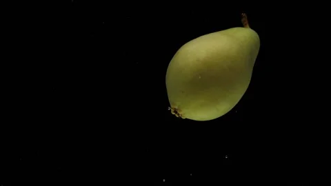 Slow motion one pear spinning falling into transparent water on black background Stock Footage 221124261