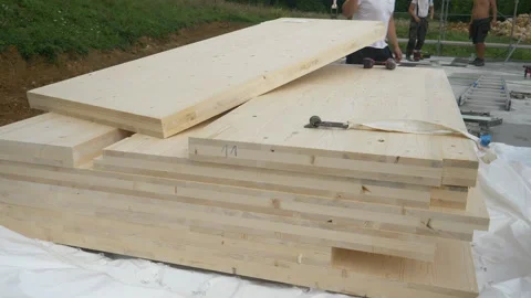 SLOW MOTION: One wood panel is lifted from the stack of CLT timber panels. Stock Footage 307880216