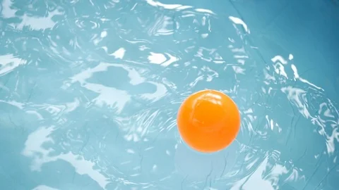 Slow motion orange ball floating on clean water of blue swimming pool Stock Footage 89210954