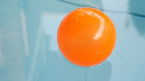 Slow motion orange ball floating on clean water of blue swimming pool Stock Footage 96289792