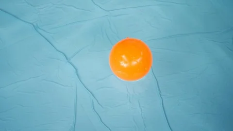 Slow motion, orange ball floating on clean water of blue swimming pool Stock Footage 113877578