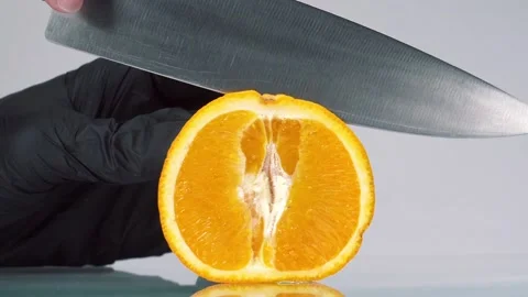 Slow motion orange cut in slow motion. Man in black gloves slice orange fruit Stock Footage 150772163