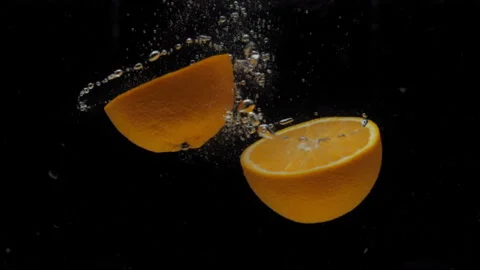Slow motion orange halves falling into transparent water on black background Stock Footage 209818509