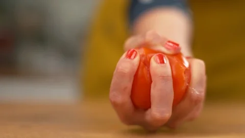 SLOW MOTION: Organic tomato explodes in a female chef's hand as she squeezes it. Stock Footage 103269998