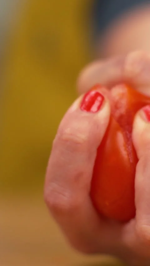 SLOW MOTION: Organic tomato explodes in a female chef's hand as she squeezes it. Stock Footage 280828676