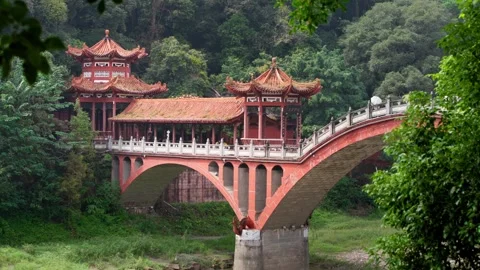 Slow motion of ornate red bridge surrounded by green forest in Leshan Stock Footage 315136521