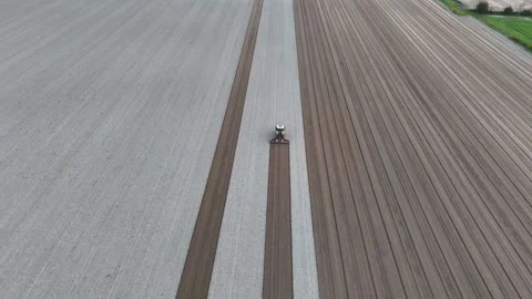 Slow motion overhead drone shot of tractor aligning striped soil bands at Stock Footage 308444179