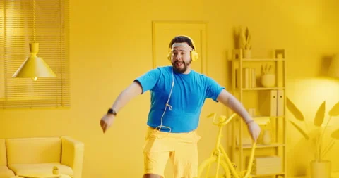 Slow motion of overweight young man practicing fitness dance while listening Stock Footage 165867616