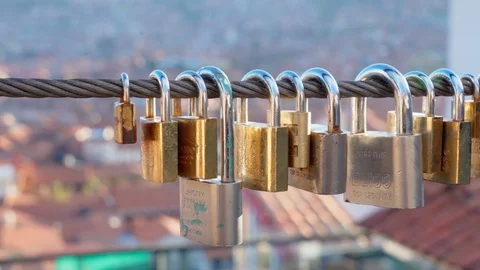 Slow motion of padlocks on steel cable in city, close-up of golden metallic Stock Footage 128852566