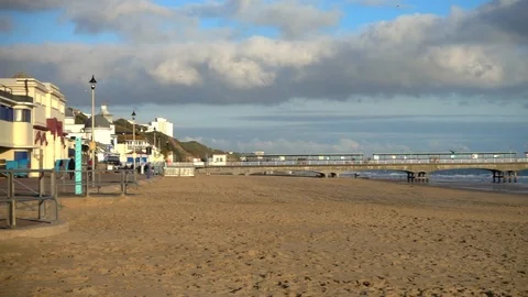 Slow motion - Pan of beach and pier, bathed in warm, autumn sunlight. Video stock 98088653