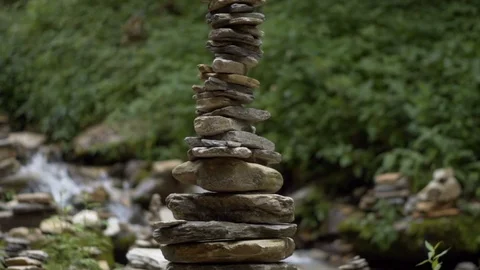 Slow motion pan of cairn balancing stones tower with river in the background Stock Footage 91434372