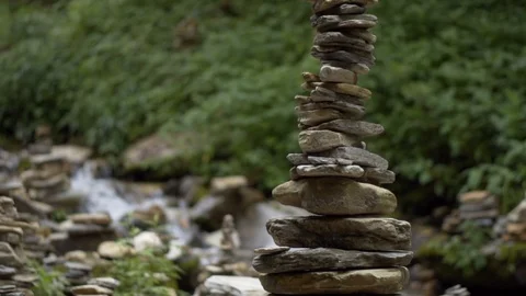 Slow motion pan of cairn balancing stones with river in the background Video stock 91434410