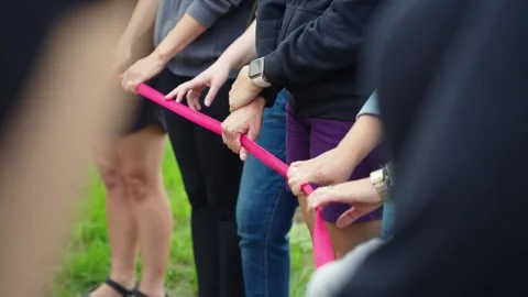Slow-motion pan down rope line of joined hands in a standing circle Stock Footage 317554190