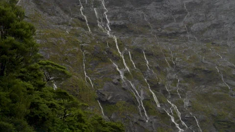 Slow motion pan (L to R) of many small waterfalls running down the cliffs Stock Footage 266913423