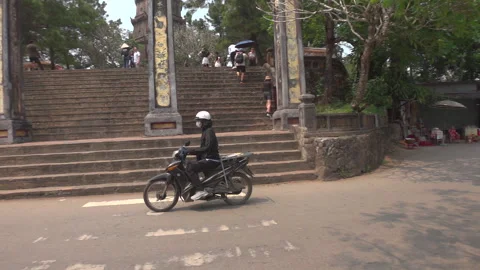Slow motion pan left follow motorbike outside pagoda temple 库存影片 271608460