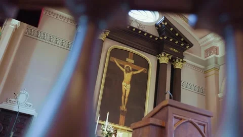 Slow-motion pan looking at Jesus on a cross through church columns during mass. Vídeo Stock 278042773